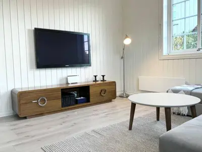 a living room with a flat screen tv on the wall at Sentral og koselig leilighet! in Lillehammer