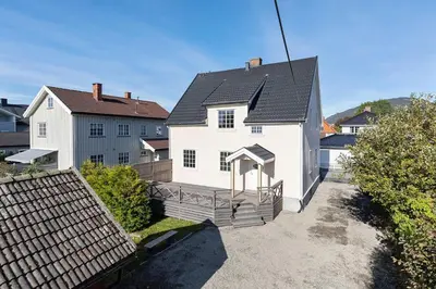 a white house with a black roof at Sentral og koselig leilighet! in Lillehammer
