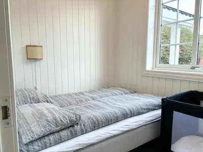 a bed sitting in a room with a window at Sentral og koselig leilighet! in Lillehammer