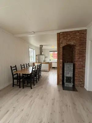 a living room with a table and a brick fireplace at Sentral og koselig leilighet! in Lillehammer