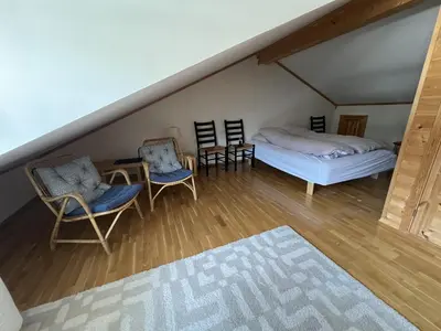 a attic room with a bed and chairs and a table at Stylish And Spacious Apartment In The Heart Of Beitostølen in Beitostøl