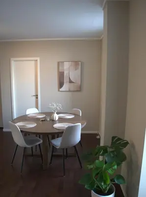 a dining room with a wooden table and white chairs at Apartment Solsiden Trondheim in Trondheim