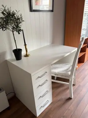 a white desk with a potted plant and a chair at Cozy apartment near city center and nature in Kristiansund