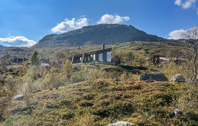 a house on a hill with a mountain in the background at Nice Home In Edland With Sauna in Nesland