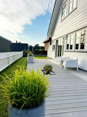 a porch with white chairs and plants on a house at Stor enebolig i Trondheim in Trondheim