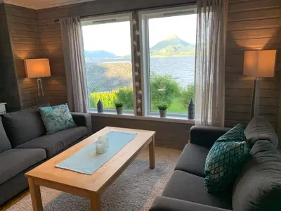 a living room with a couch and a coffee table at Villa med sauna ute, egen båt, naust og kai in Breidvik