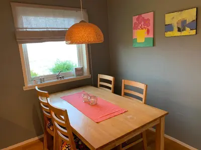 a dining room table with a pink napkin and a window at Villa med sauna ute, egen båt, naust og kai in Breidvik