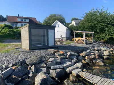 a tiny house sitting on top of a pile of rocks at Villa med sauna ute, egen båt, naust og kai in Breidvik