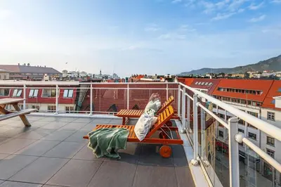 a woman sitting on a chair on a balcony at Flat in Bergen house with outstanding roof terrace in Bergen