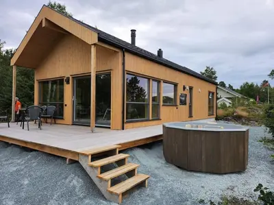 a house with a wooden deck and a table at Nyoppført hytte med mulighet til å leie badestamp in Levanger