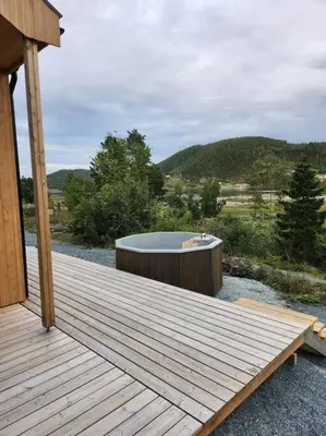 a wooden deck with a bath tub on a hill at Nyoppført hytte med mulighet til å leie badestamp in Levanger
