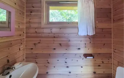 a bathroom with wooden walls and a sink and a window at 3 Bedroom Amazing Home In Reksteren in Haukafer