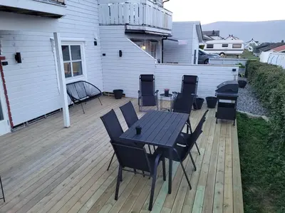 a patio with a table and chairs on a deck at Hareid in Hareid