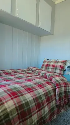 a bedroom with a bed with a plaid blanket at Room In Handsome Haven House in Gjøvik