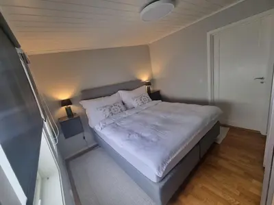 a bedroom with a large bed with white sheets and pillows at Koselig familiebolig Granåsen in Trondheim