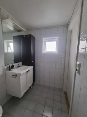 a white bathroom with a sink and a mirror at Koselig familiebolig Granåsen in Trondheim