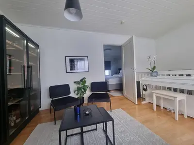 a living room with a table and chairs and a bedroom at Koselig familiebolig Granåsen in Trondheim