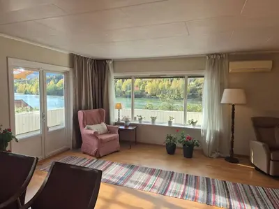 a living room with a chair and large windows at Cozy Home with Sauna, river views and 10 min from Hafjell and Lillehammer in Fåberg