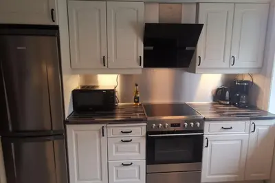 a kitchen with white cabinets and a stainless steel refrigerator at Koselig leilighet nær sentrum in Laksevag