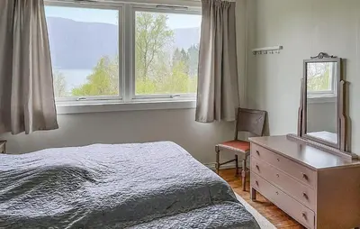 a bedroom with a bed and a dresser and a window at Lovely Home In Sørbøvåg in Sørbø