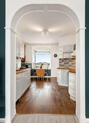 an archway in a kitchen with white cabinets and a table at Flott leilighet med herlig utsikt in Ålesund