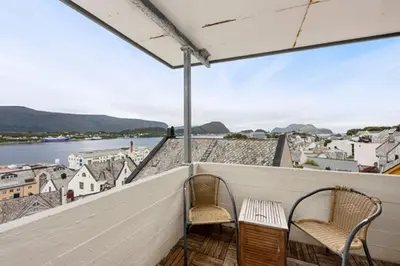 a balcony with two chairs and a view of the water at Flott leilighet med herlig utsikt in Ålesund