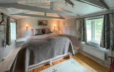 a bedroom with a bed and two windows at Cozy Home In Sjusjøen With Sauna in Sjusjøen