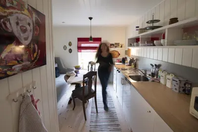 a woman standing in a kitchen with a table at Koselig leilighet i sentrum in Ålesund