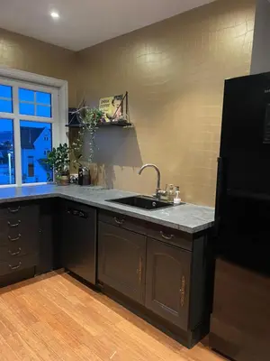 a kitchen with a sink and a black refrigerator at Villa apartment in Trondheim