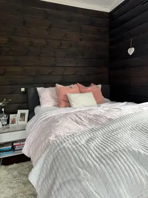 a bedroom with a bed with a wooden wall at Villa apartment in Trondheim