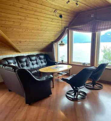 a living room with a leather couch and a table at Seaside 3-bedroom Holiday home in Balestrand