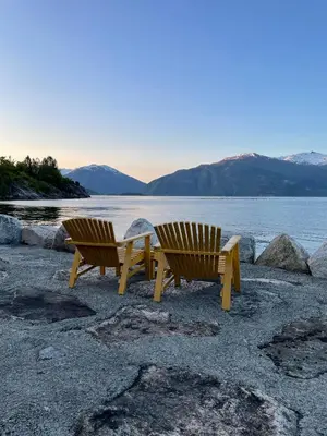 two benches sitting on a beach near the water at Seaside 3-bedroom Holiday home in Balestrand
