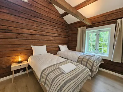two beds in a room with wooden walls at Stort hus med 2 leiligheter til leie på Lundamo, Perfekt for større grupper! in Melhus