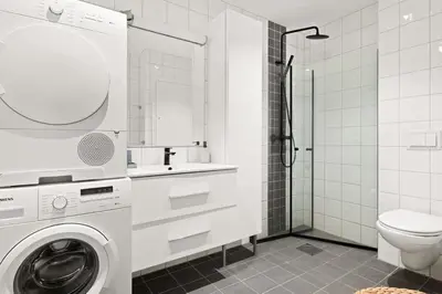 a bathroom with a washing machine and a toilet at Dining Apartments l Restaurants with sea I City Traveller & Workspace in Bergen