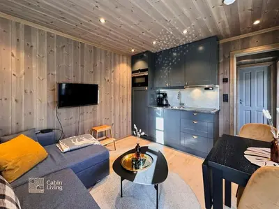 a living room with a blue couch and a kitchen at Modern apartment with ski in out in Hafjell in Hafjell