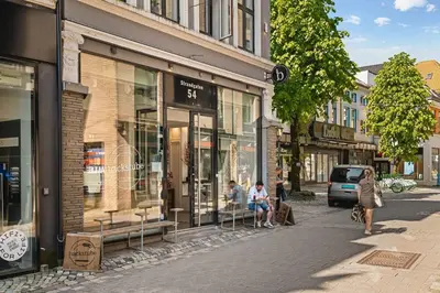 a group of people sitting outside a store on a street at Dinbnb Appartments l Traditional bergenshouse I Charming I Familiy in Bergen