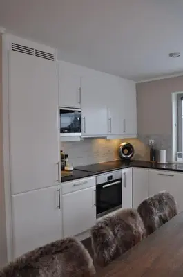 a kitchen with white cabinets and a table and chairs at Leilighet sentralt på Sjusjøen, 11 sengeplasser in Ringsaker