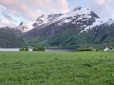 a snow covered mountain with a field and a lake at Jovollstua i Eresfjord med båt til leie in Øverås