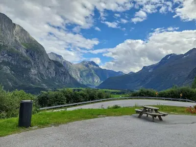 a picnic table next to a road with mountains at Jovollstua i Eresfjord med båt til leie in Øverås