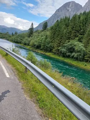 a river next to a road next to a river at Jovollstua i Eresfjord med båt til leie in Øverås