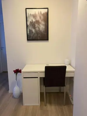 a white desk with a chair and a vase of flowers at 2 Bedroom Apartment Located Downtown Trondheim in Trondheim