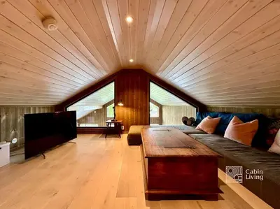 a large living room with a couch and a tv at Modern cabin Skeikampen with ski-in out cross country trails & great view in Aulstad