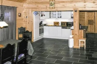 a kitchen with white cabinets and a black tile floor at Coazy cabin with sauna in Trysil