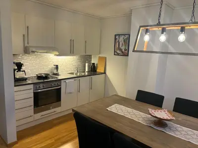 a kitchen with white cabinets and a wooden table at Røldal a home with a view in Håra