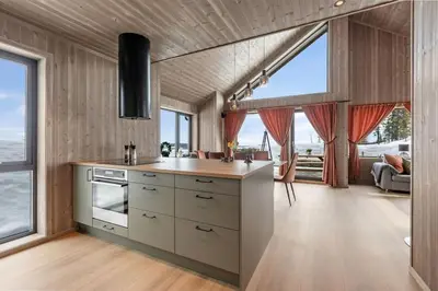 a kitchen with wooden walls and large windows at Ny moderne hytte i Aust-Torpa in Aust-Torpa