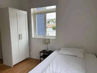 a white bedroom with a bed and a window at Bendixens vei 57 in Bergen