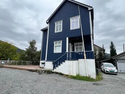 a blue house with a car parked in front of it at Bendixens vei 57 in Bergen