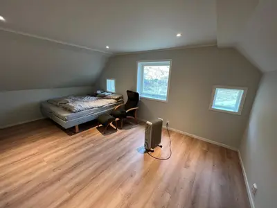 a bedroom with a bed and a chair and a radiator at Hus i Syvde in Sylte