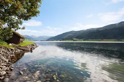 a lake with a house and a boat in the water at Voss- Myrkdalen Lodge in Vossestrand