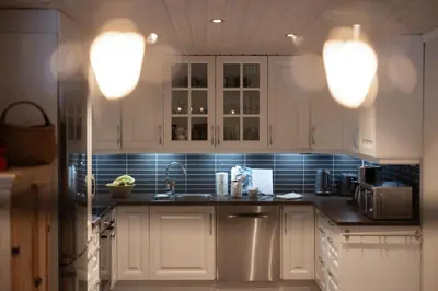 a kitchen with white cabinets and blue tiled walls at Skoglund privat Villa in Trysil
